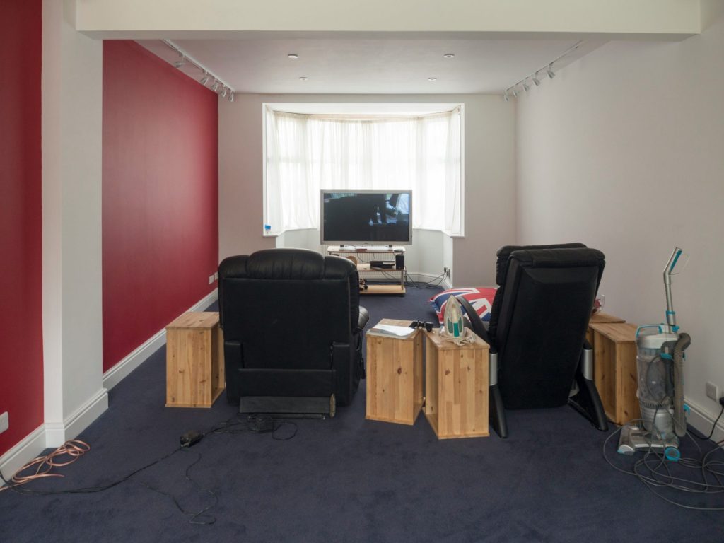 Salon avec fauteuils, télévision et mur rouge.