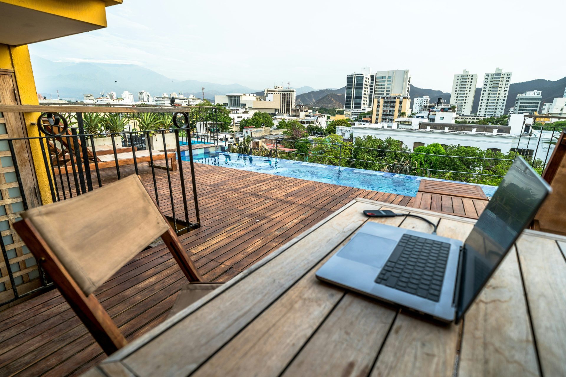 Laptop on wooden deck overlooking city and pool