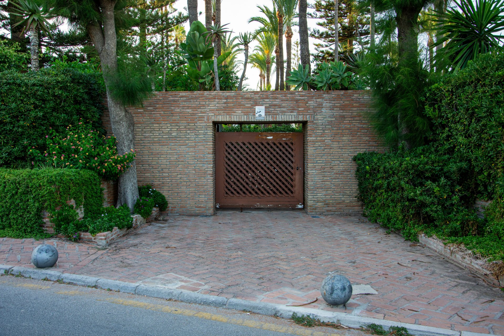Rustic wooden gate in a brick wall with lush greenery.